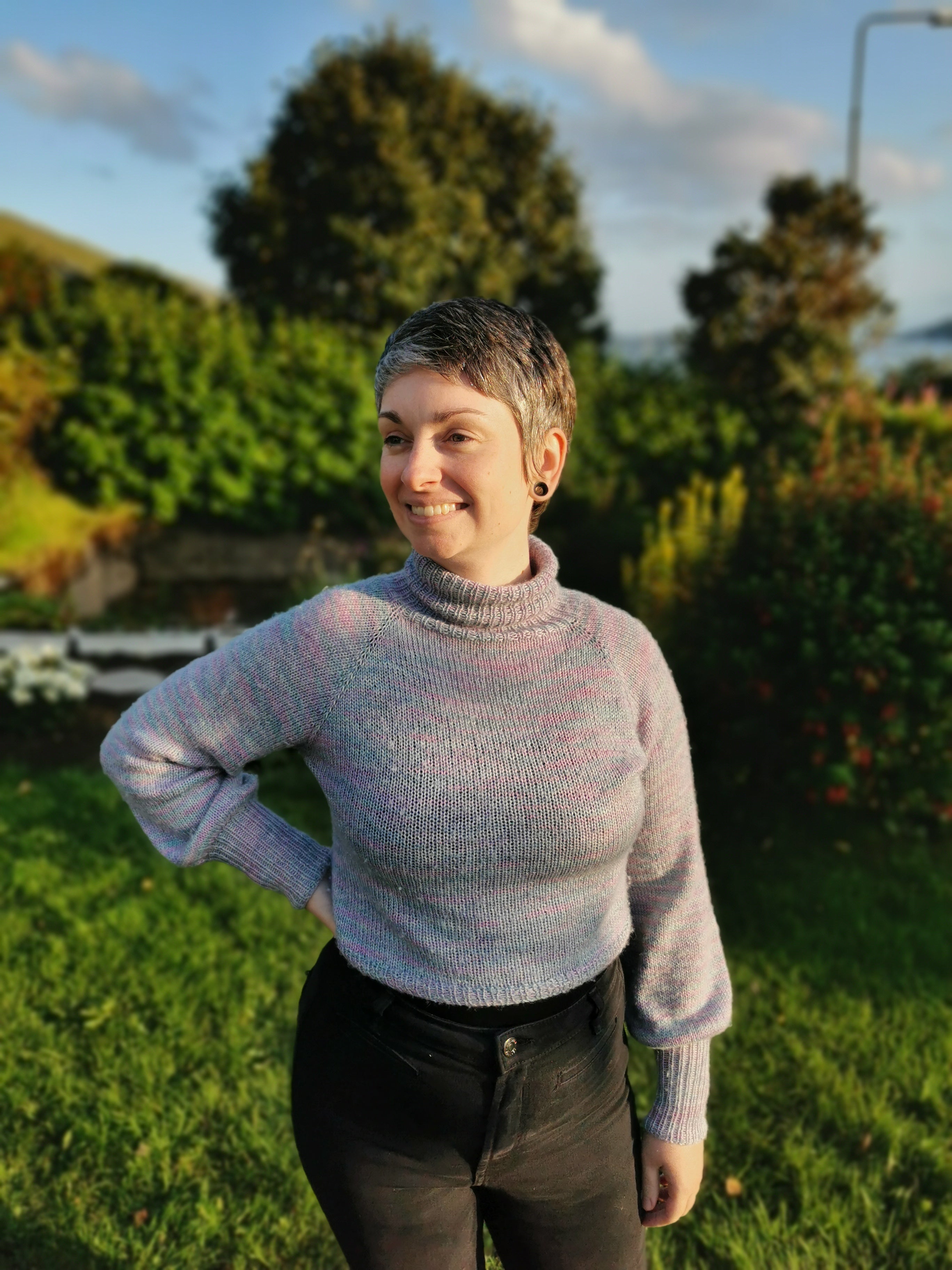 Mynd av Rúnu. Hon stendur í havanum og smílist, meðan hon hevur aðra hondina hvílandi niður á mjødnina. Hon er í eini troyggju við høgum hálsi, sum hon sjálv hevur bundið. Troyggjan er ljós-lilla og ljósablá. 