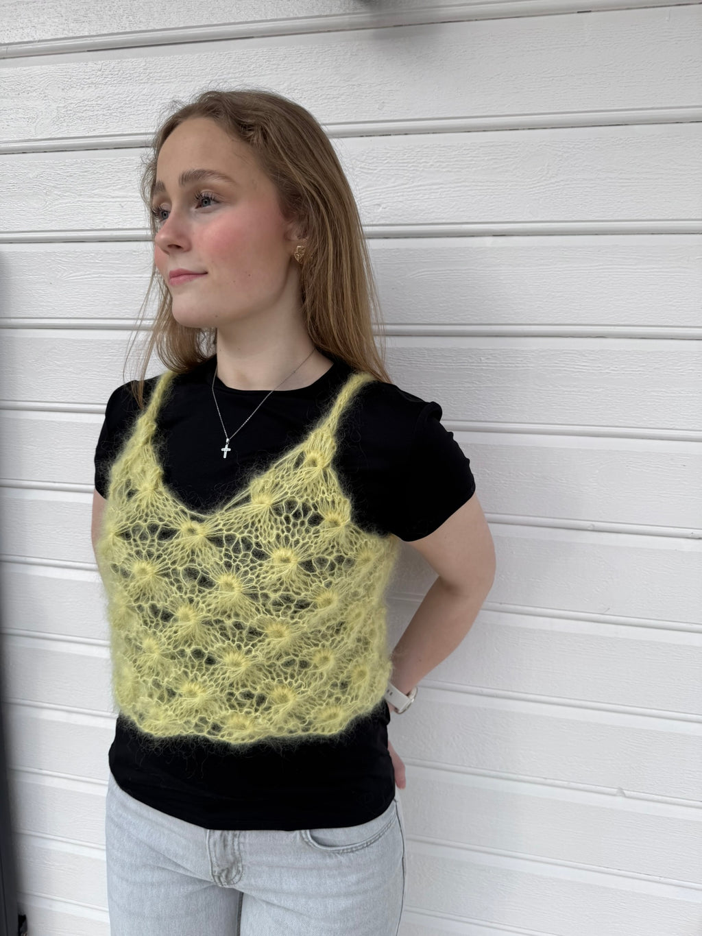 Person wearing a yellow knitted top against a white background
