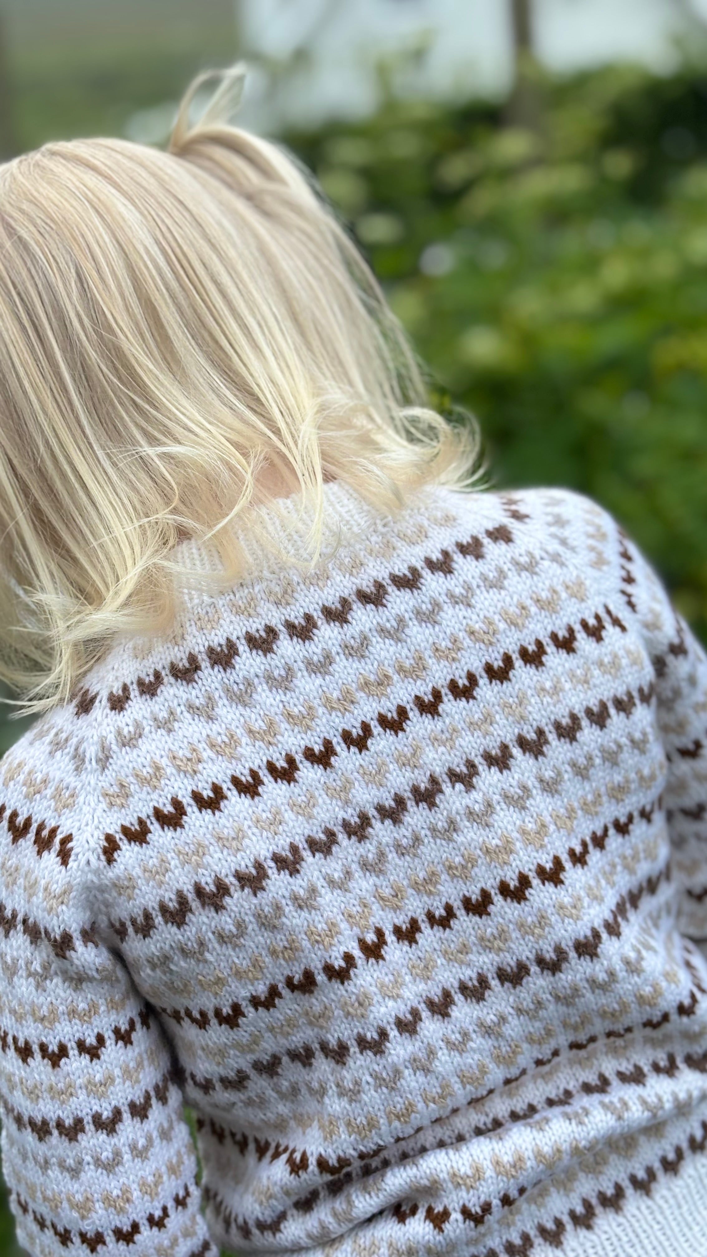 Child wearing a patterned sweater with blurred background