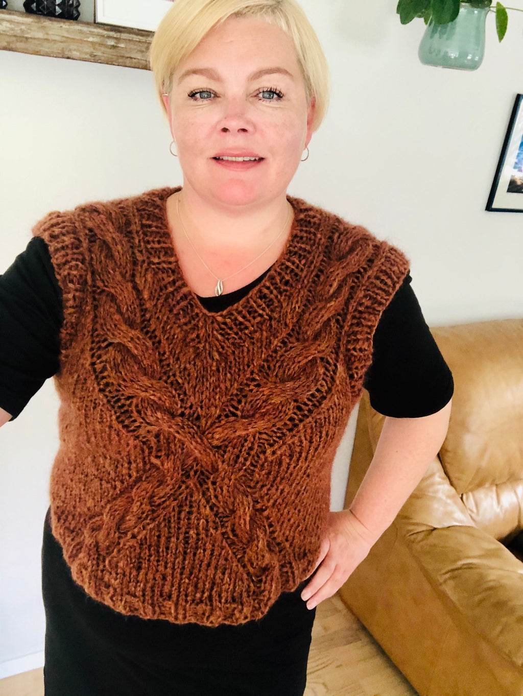 Kristianna er í einum reyð-brúnum vesti, sum hevur eitt snar-mynstur á forsíðuni, sum skapar ein kross. 