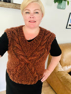 Kristianna er í einum reyð-brúnum vesti, sum hevur eitt snar-mynstur á forsíðuni, sum skapar ein kross. 