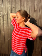 Person wearing a red and white striped shirt against a wooden fence.