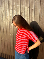 Person wearing a red and white striped shirt against a house.