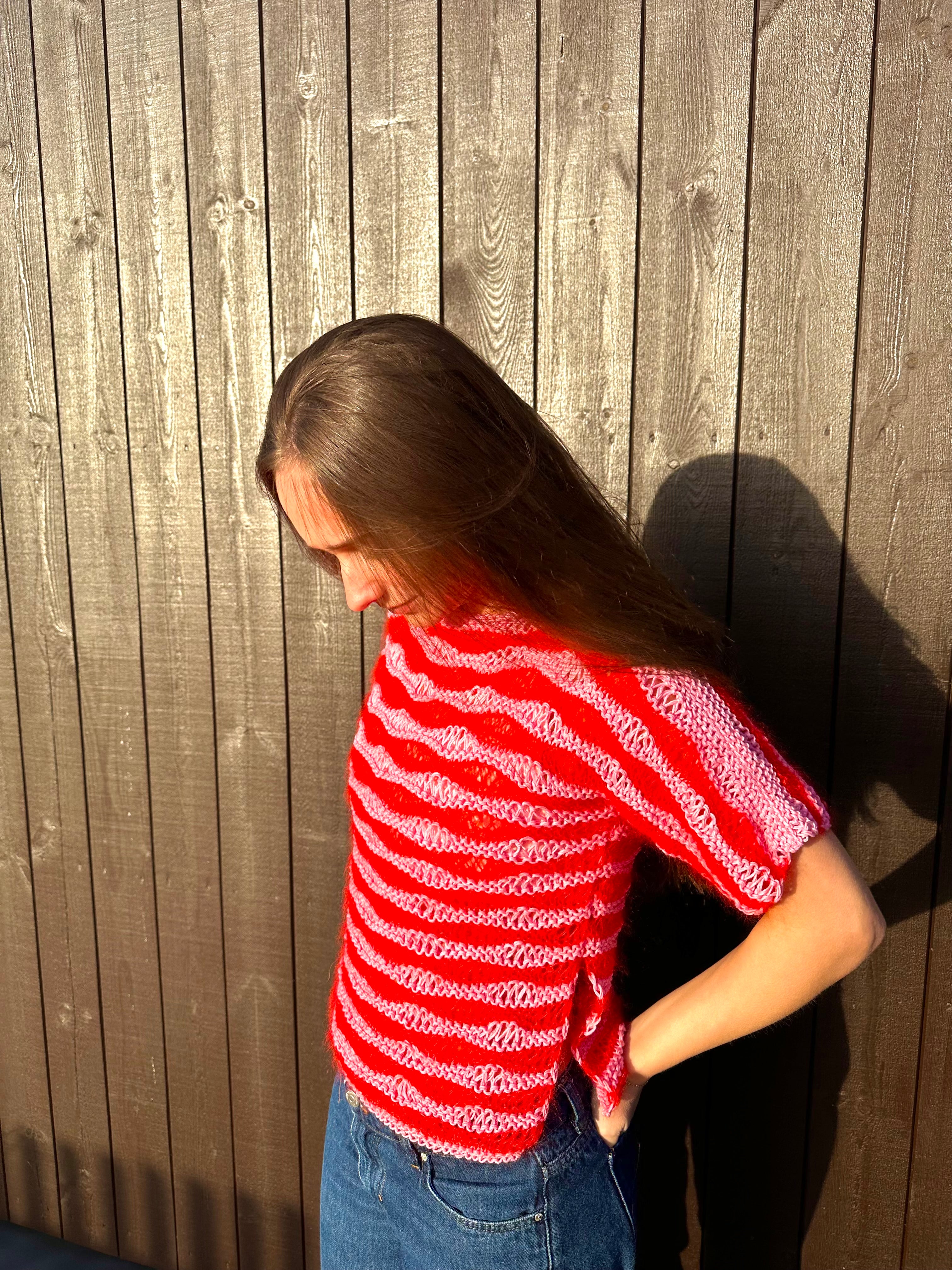 Person wearing a red and white striped shirt against a house.