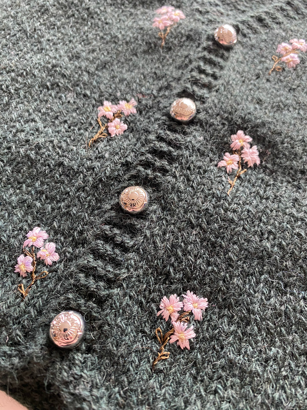 Close-up of a textured fabric surface with pink floral patterns and metallic buttons.